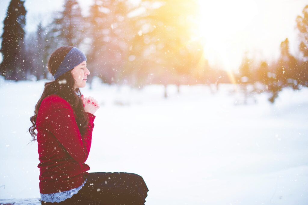 Woman praying in the snow on her knees