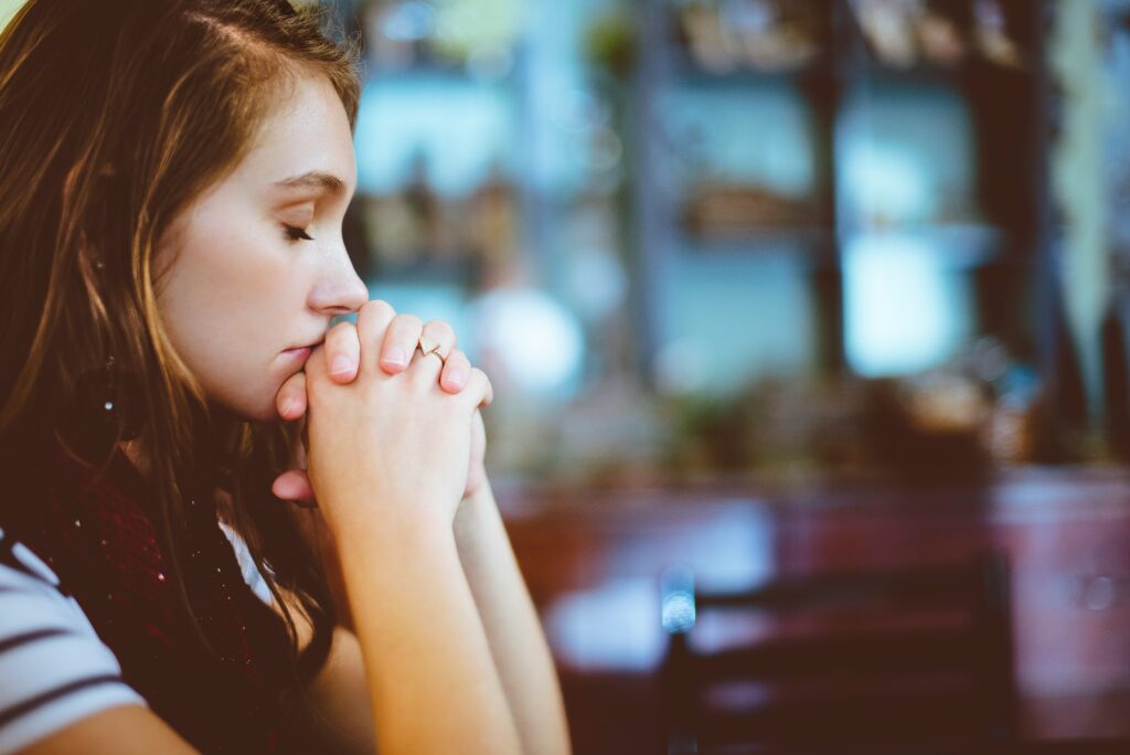 Close-up of a woman praying with her eyes closed and hands folded