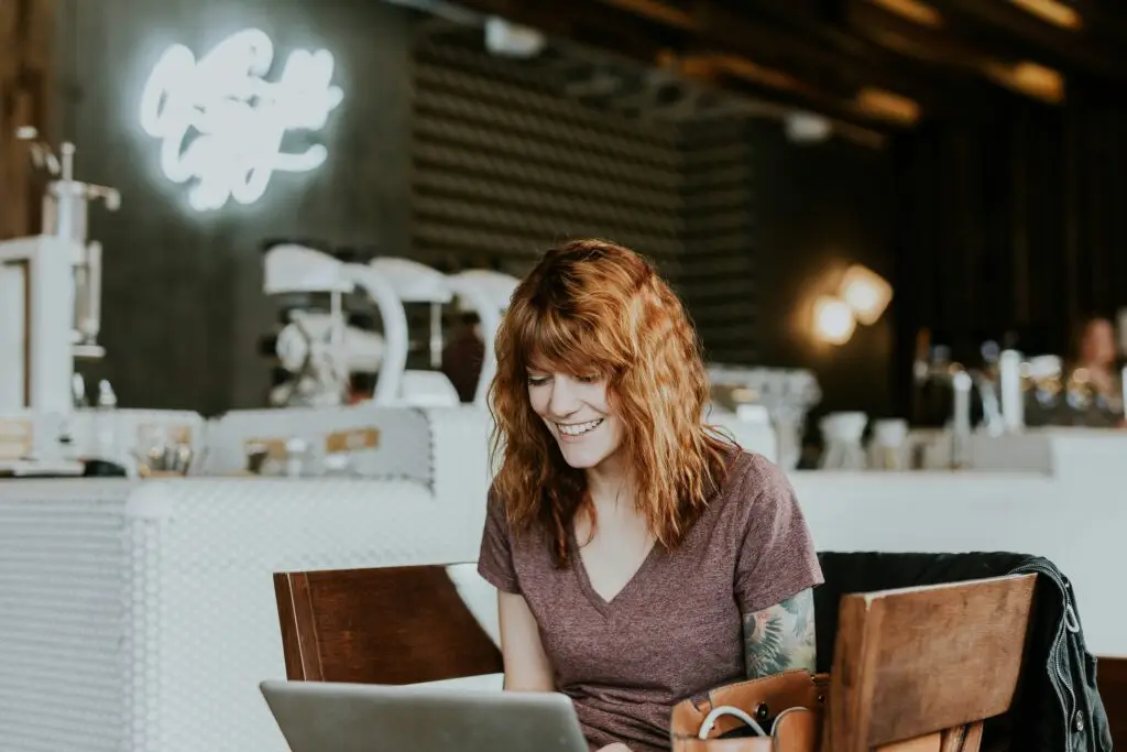 Happy woman sitting in a restaurant, working on her laptop