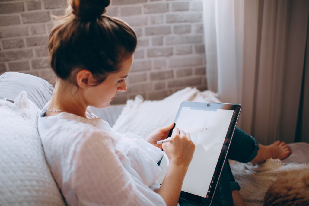 Woman writing and drawing in her manifestation journal on an iPad