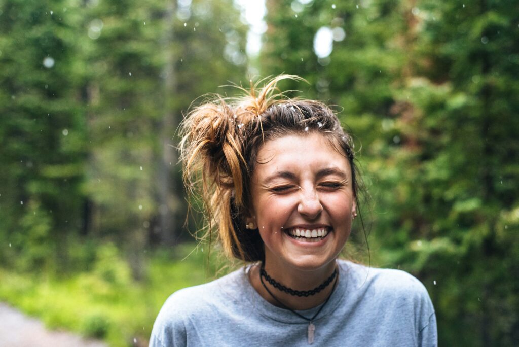 Happy woman in the rain in a forest, smiling