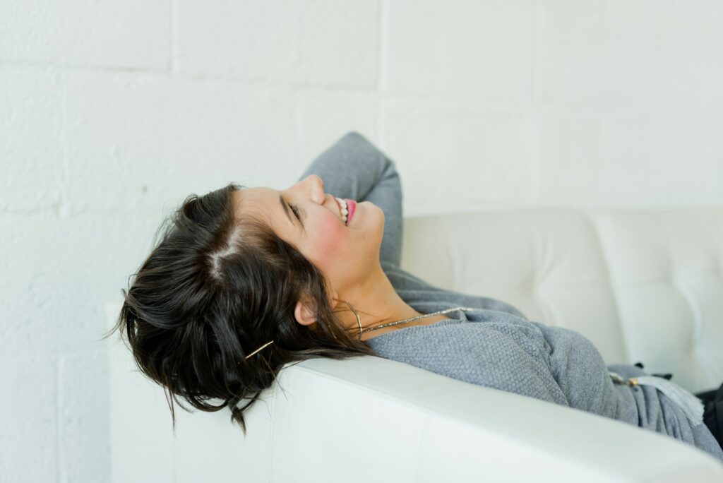 Woman lying on the couch laughing 