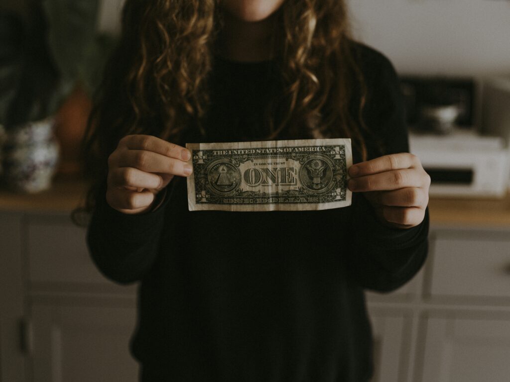 Woman holding a one dollar bill in her hands