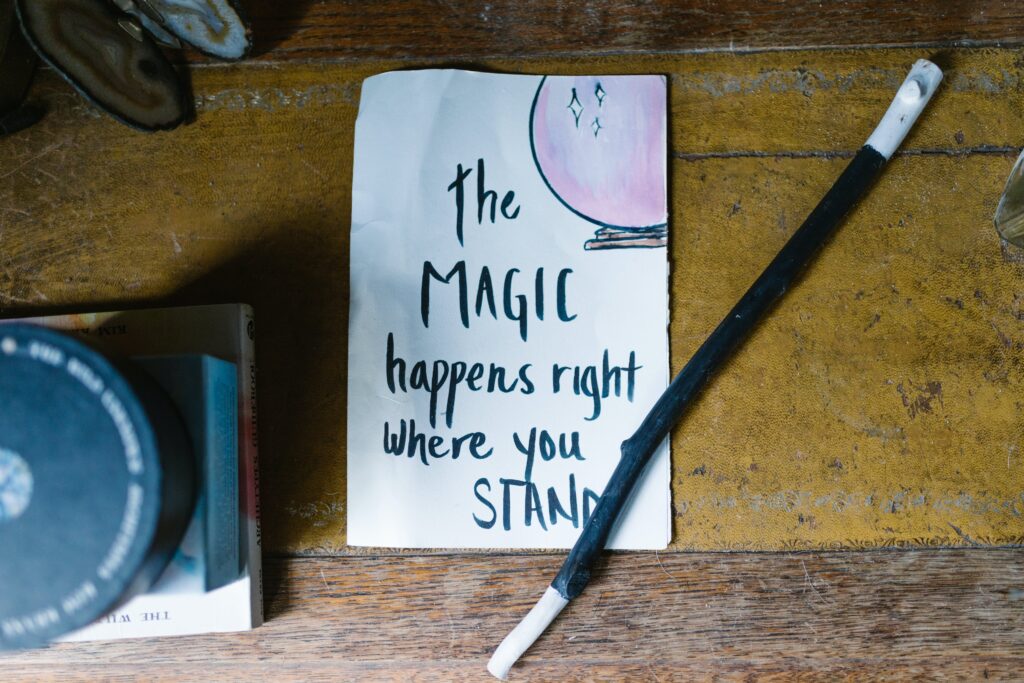 Piece of paper on a table with a magic wand, with the text "The magic happens right where you stand"