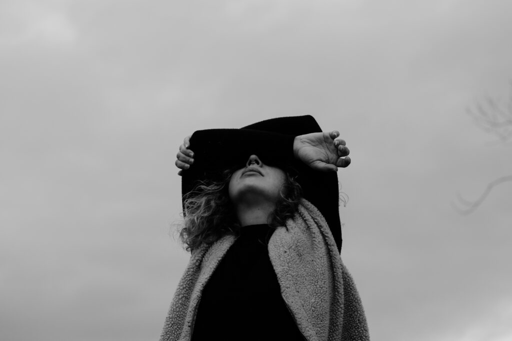 Woman crossing her arms over her eyes looking up into the grey sky